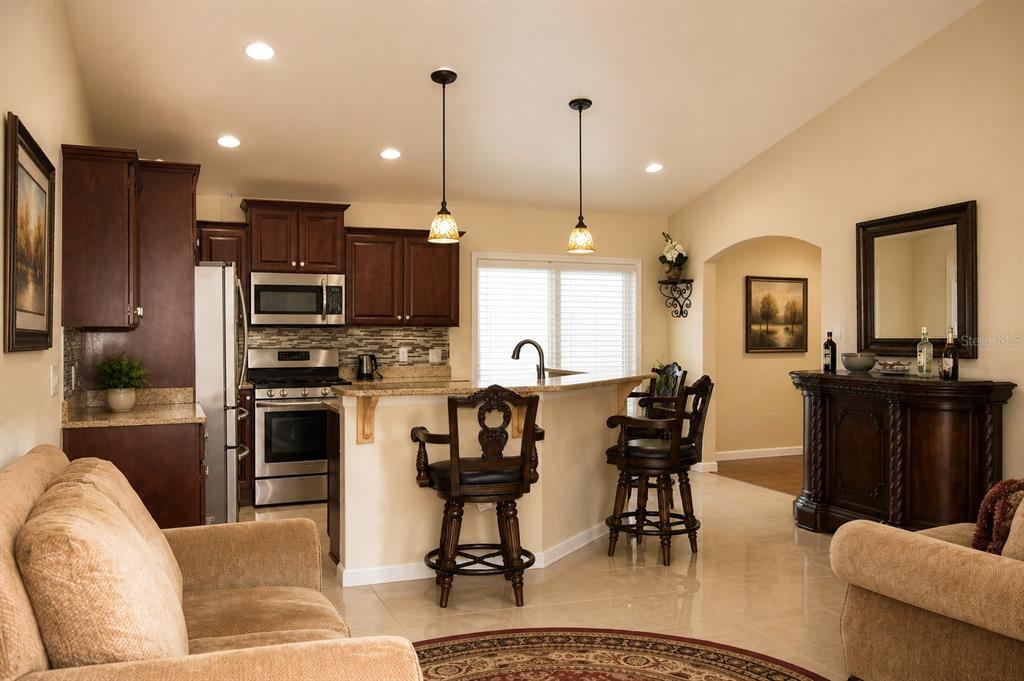 A kitchen with dark wood cabinets, granite countertops, and a breakfast bar with two stools — 4714 SW 114TH PLACE, OCALA, FL