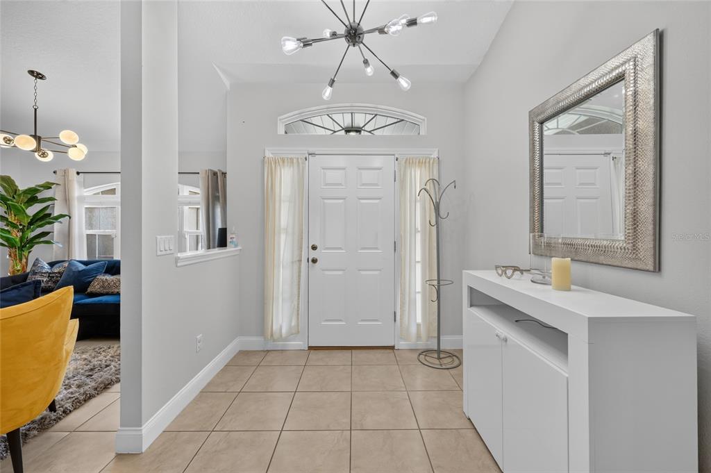 A bright entryway features tile flooring, a white console table, and a modern light fixture — 5294 SW 97TH LANE ROAD, OCALA, FL