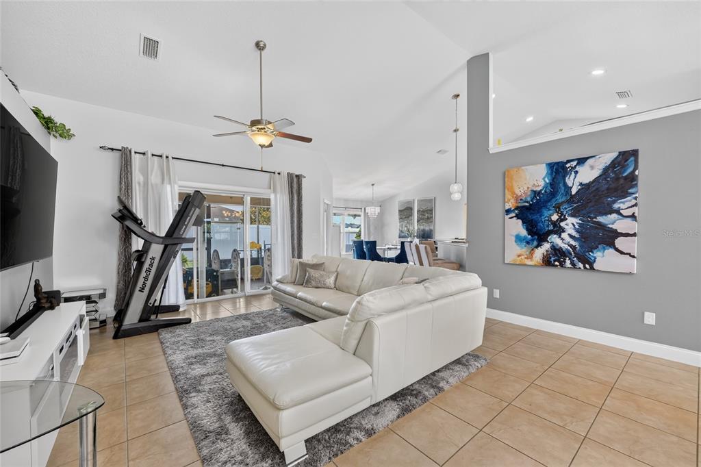 A living room features a white sectional sofa, a treadmill, and a large abstract painting — 5294 SW 97TH LANE ROAD, OCALA, FL