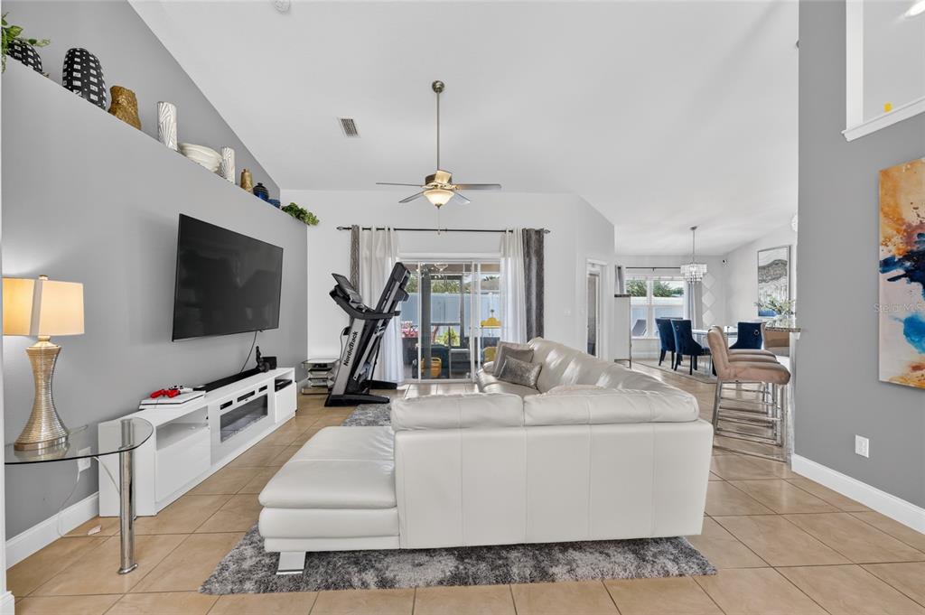 A living room features a white sectional sofa, a treadmill, and a wall-mounted television — 5294 SW 97TH LANE ROAD, OCALA, FL