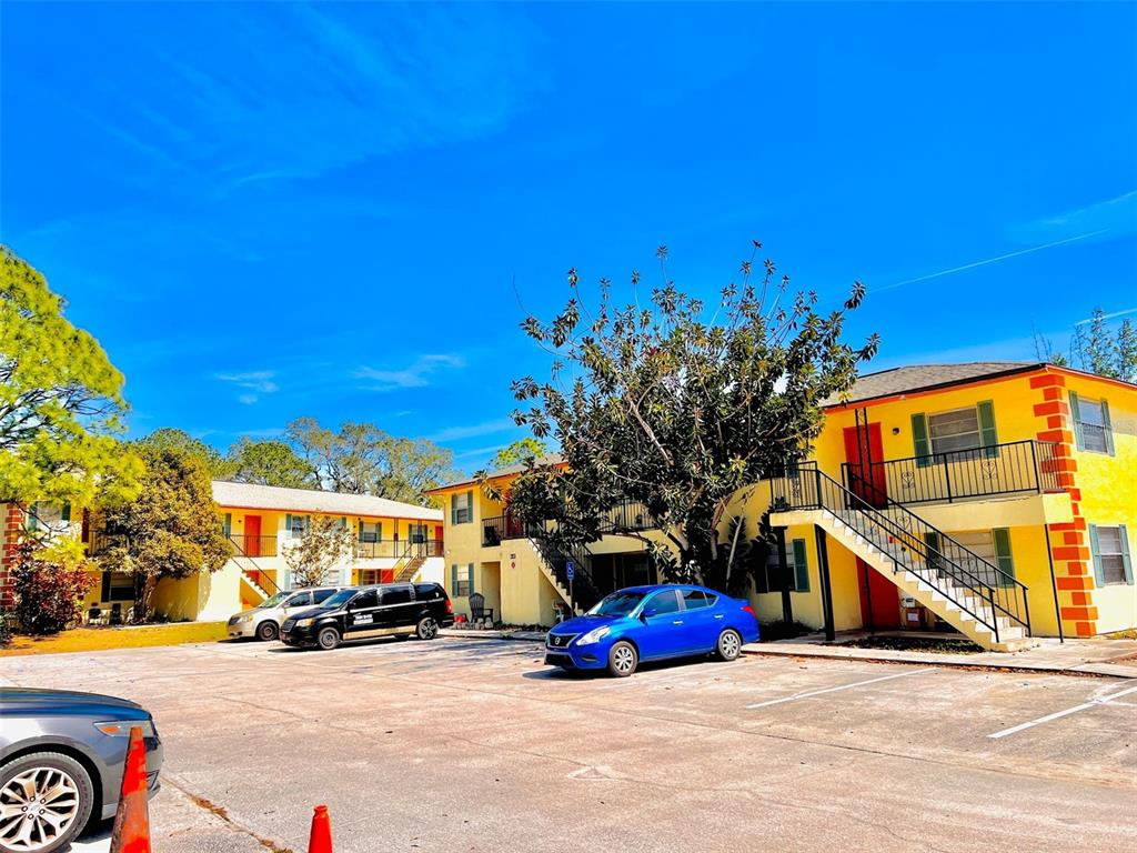 Exterior view of two-story yellow apartment buildings with outdoor staircases and a parking lot — 2190 KNOX MCRAE DRIVE UNIT F, TITUSVILLE, FL