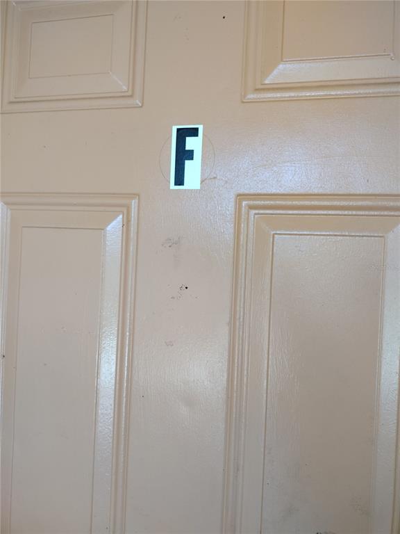 A close-up view of a beige, paneled door featuring a black letter F sticker — 2190 KNOX MCRAE DRIVE UNIT F, TITUSVILLE, FL