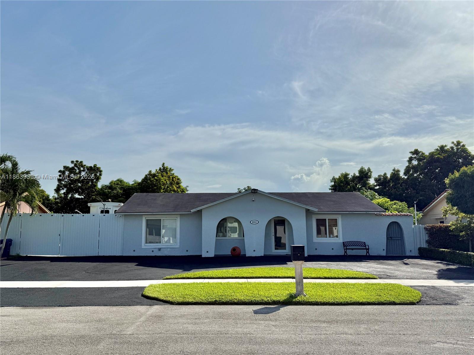 A single-story house with a light-colored facade, arched entryways, and a paved front driveway — 6553 SW 148th Pl, Miami FL 33193, MIAMI, FL