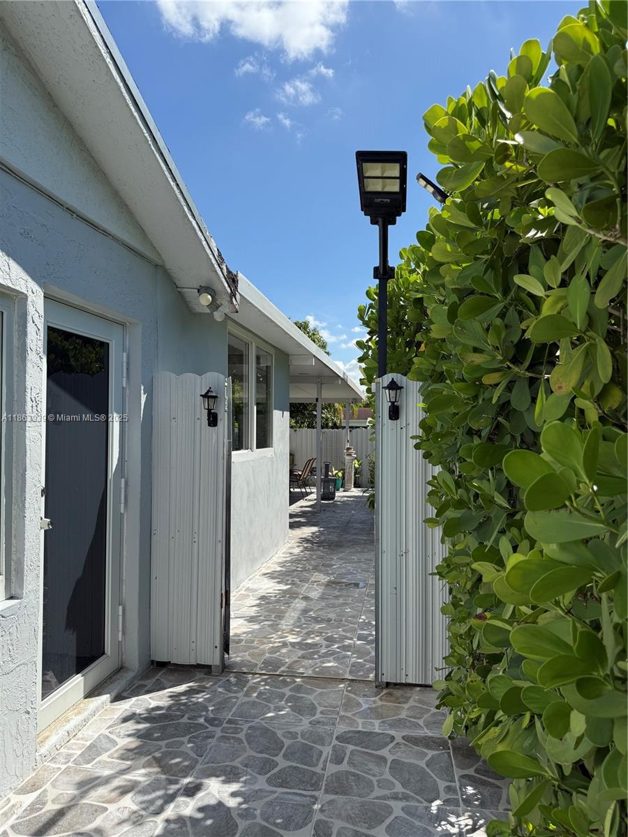 A paved walkway leads between a light-colored house exterior and a tall green hedge — 6553 SW 148th Pl, Miami FL 33193, MIAMI, FL