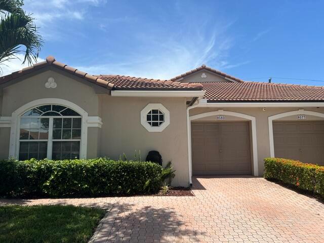 A beige house with a tiled roof, two garage doors, and a manicured hedge — 8583 Vía Serena, Boca Raton FL 33433, BOCA RATON, FL