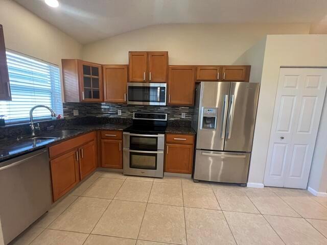 A kitchen features wood cabinets, stainless steel appliances, a tiled floor, and a pantry door — 8583 Vía Serena, Boca Raton FL 33433, BOCA RATON, FL
