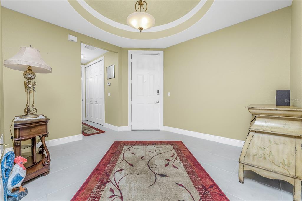 An entryway features a tiled floor, a central rug, a white door, and light-colored walls — 3311 PURPLE MARTIN DRIVE UNIT 126, PUNTA GORDA, FL