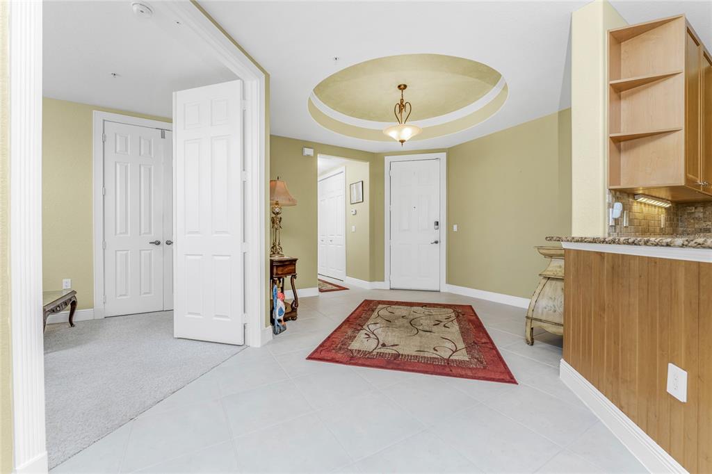 An entryway features a circular tray ceiling, tile flooring, a red rug, and white doors — 3311 PURPLE MARTIN DRIVE UNIT 126, PUNTA GORDA, FL