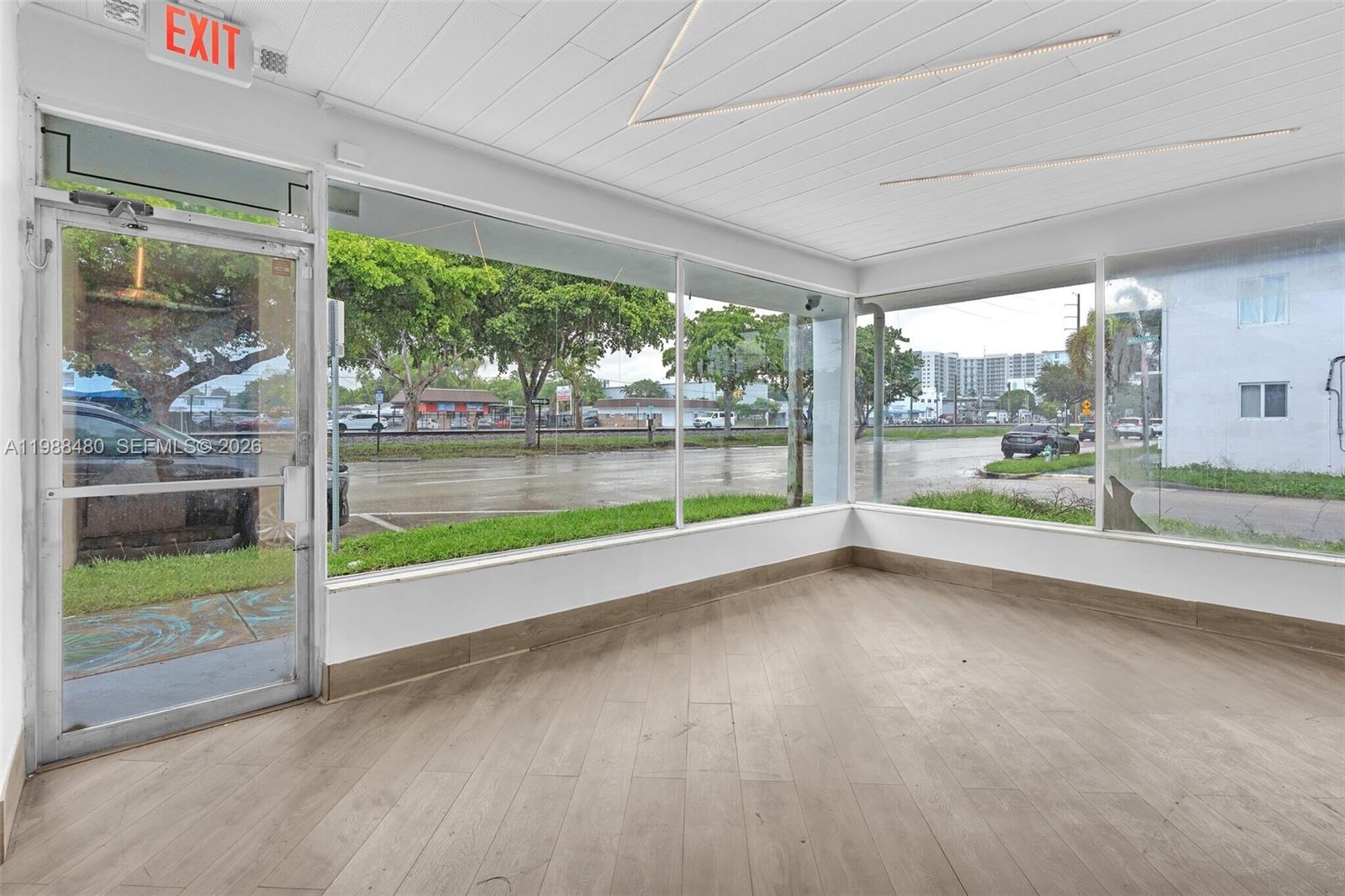 This empty commercial space features large windows, light wood-look flooring, and a white ceiling — 601 S 21st Ave, Hollywood FL 33020, HOLLYWOOD, FL