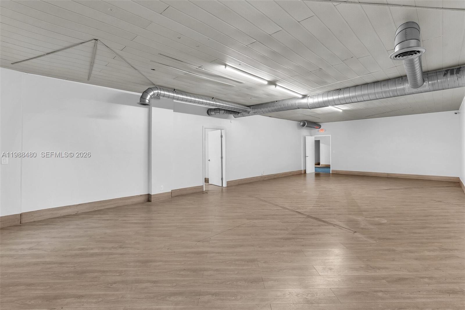 An empty commercial room features light wood-look flooring, white walls, and exposed ceiling ductwork — 601 S 21st Ave, Hollywood FL 33020, HOLLYWOOD, FL
