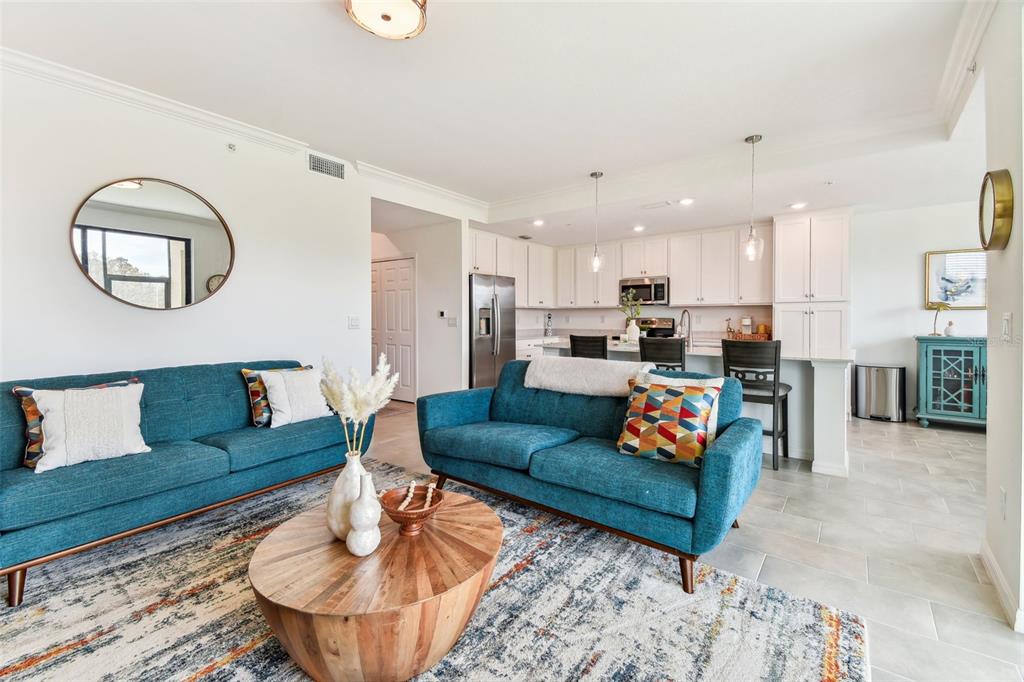 A living room with two blue sofas, a wooden coffee table, and an open kitchen — 18114 GAWTHROP DRIVE UNIT 106, BRADENTON, FL