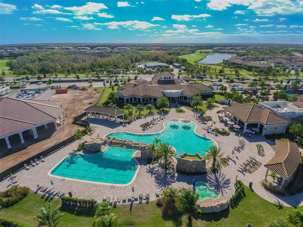 An aerial view shows a community clubhouse with a large pool, rock features, and landscaping — 18114 GAWTHROP DRIVE UNIT 106, BRADENTON, FL