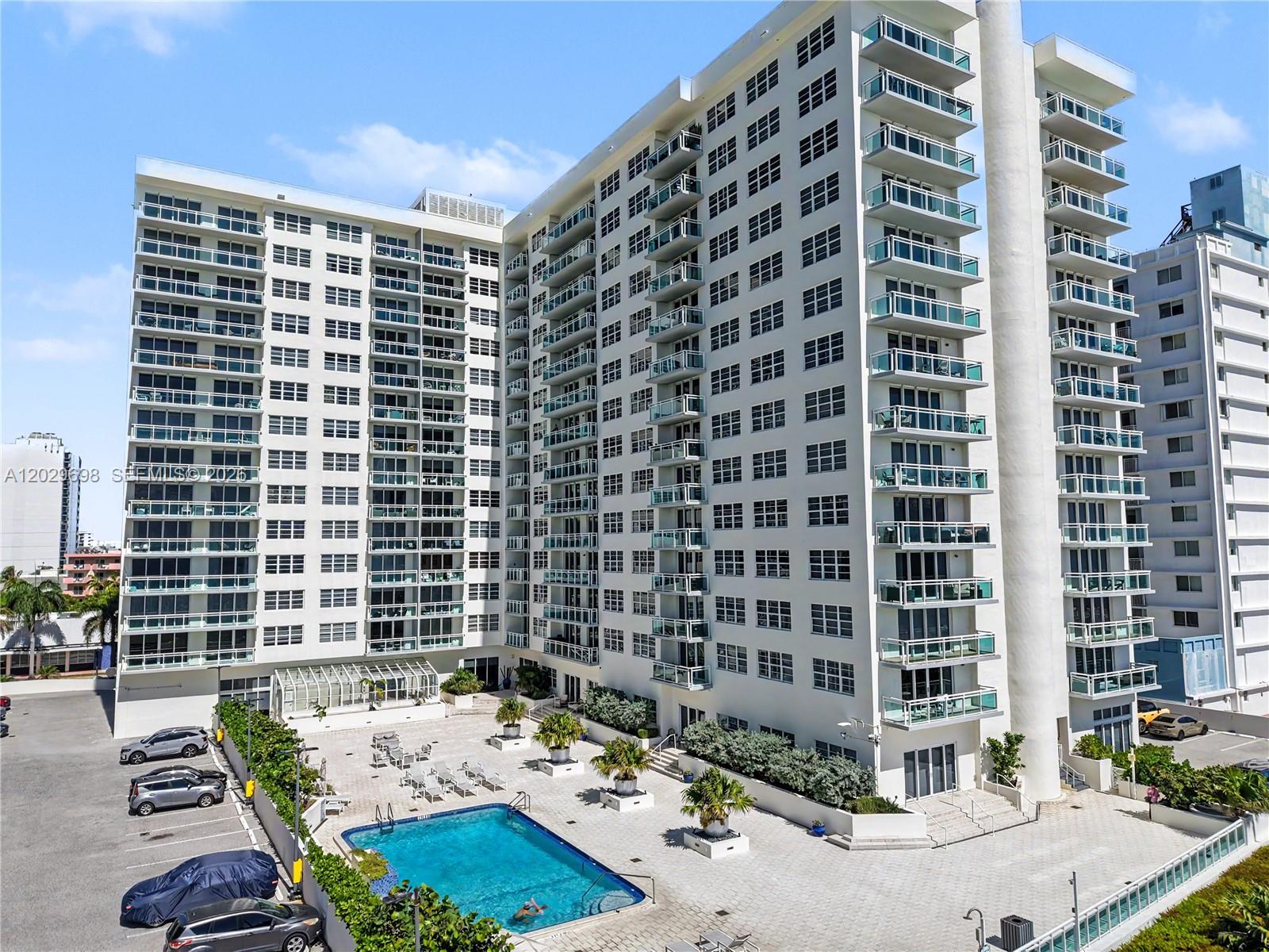 An exterior view of a multi-story apartment building featuring a swimming pool and parking lot — 6917 Collins Ave # 605, Miami Beach FL 33141, MIAMI BEACH, FL