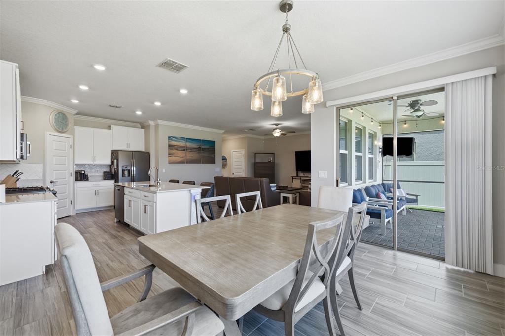 A dining area with a wooden table and chairs opens to a kitchen and patio — 2920 GRIDIRON ISLE, NEW PORT RICHEY, FL