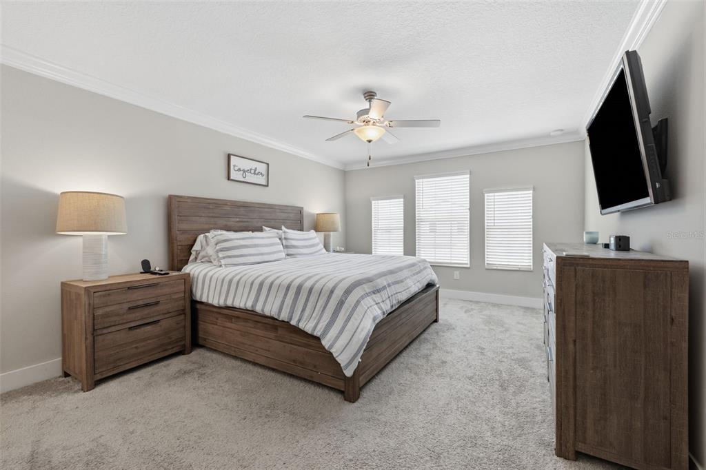 A bedroom features a wooden bed frame, matching nightstands, a dresser, and a ceiling fan — 2920 GRIDIRON ISLE, NEW PORT RICHEY, FL