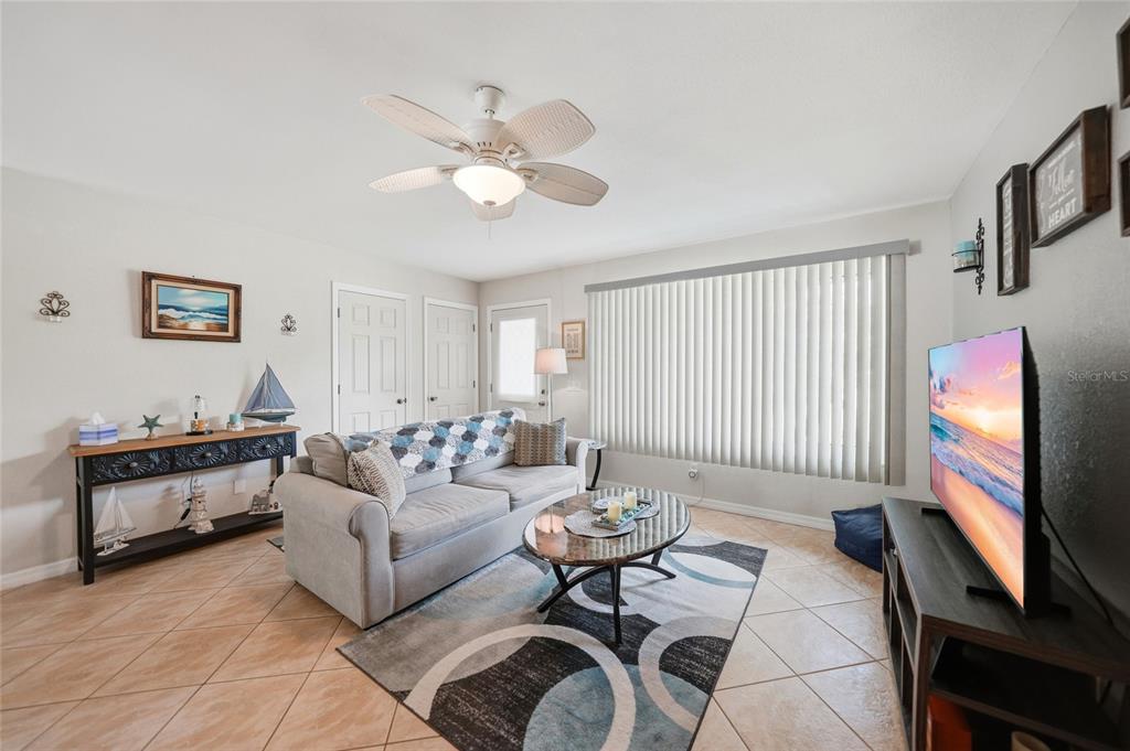 A living room features tile flooring, a ceiling fan, a sofa, and a television — 20341 XITA AVENUE, PORT CHARLOTTE, FL