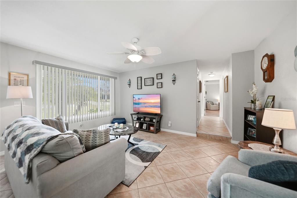 A living room features light gray walls, tile flooring, a ceiling fan, and a television — 20341 XITA AVENUE, PORT CHARLOTTE, FL