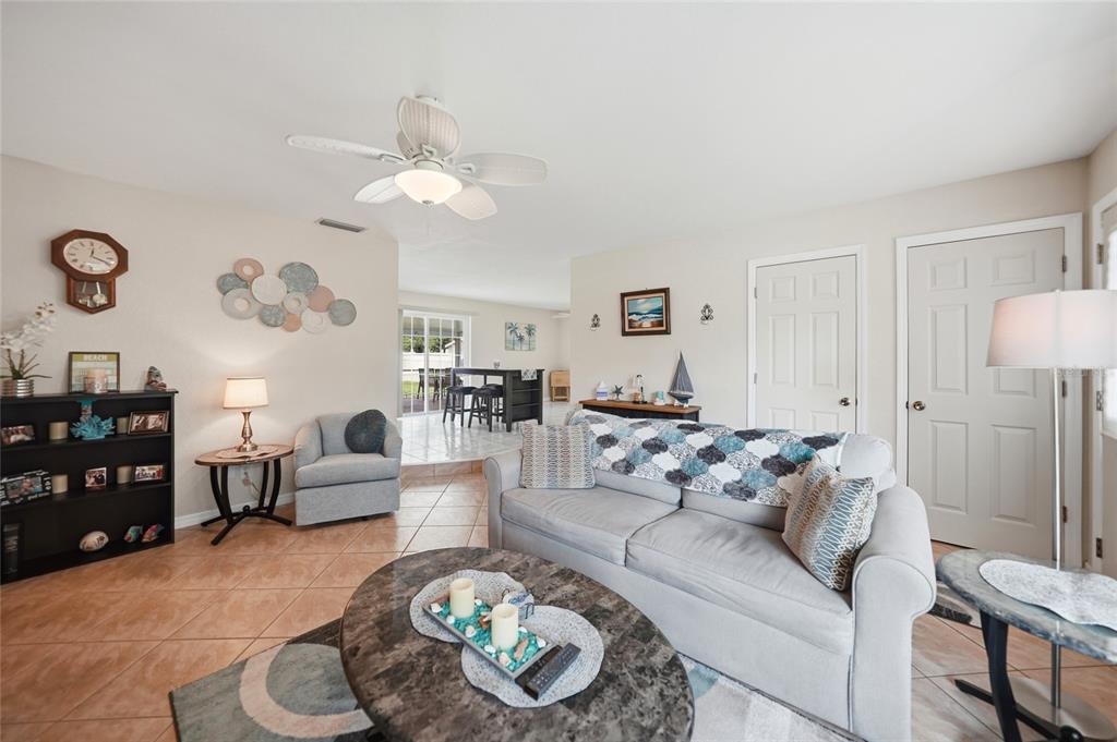 A living room features tile flooring, a gray sofa, a ceiling fan, and a bookshelf — 20341 XITA AVENUE, PORT CHARLOTTE, FL