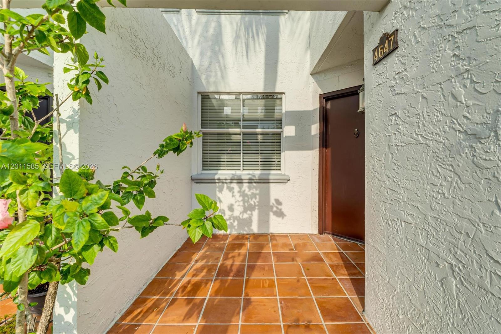 A tiled entryway features a brown front door, a window with blinds, and exterior stucco — 4647 NW 97th Pl # 151, Doral FL 33178, DORAL, FL