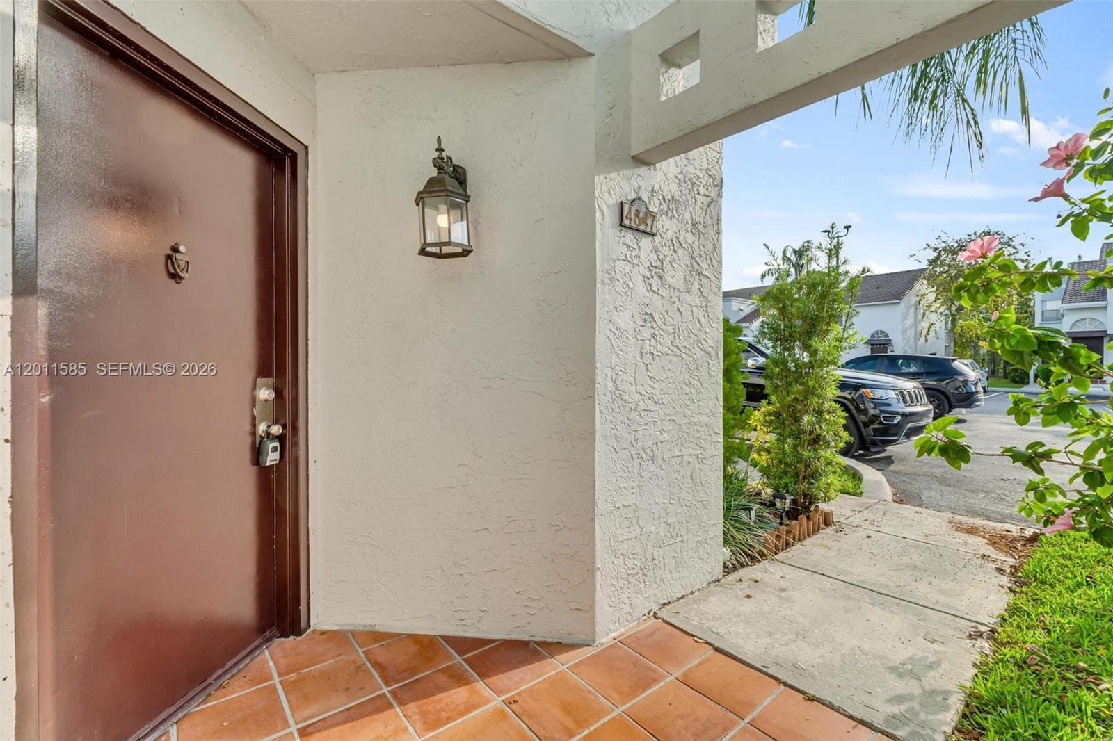 The exterior entryway features a brown door, tiled floor, wall-mounted light, and address plaque — 4647 NW 97th Pl # 151, Doral FL 33178, DORAL, FL