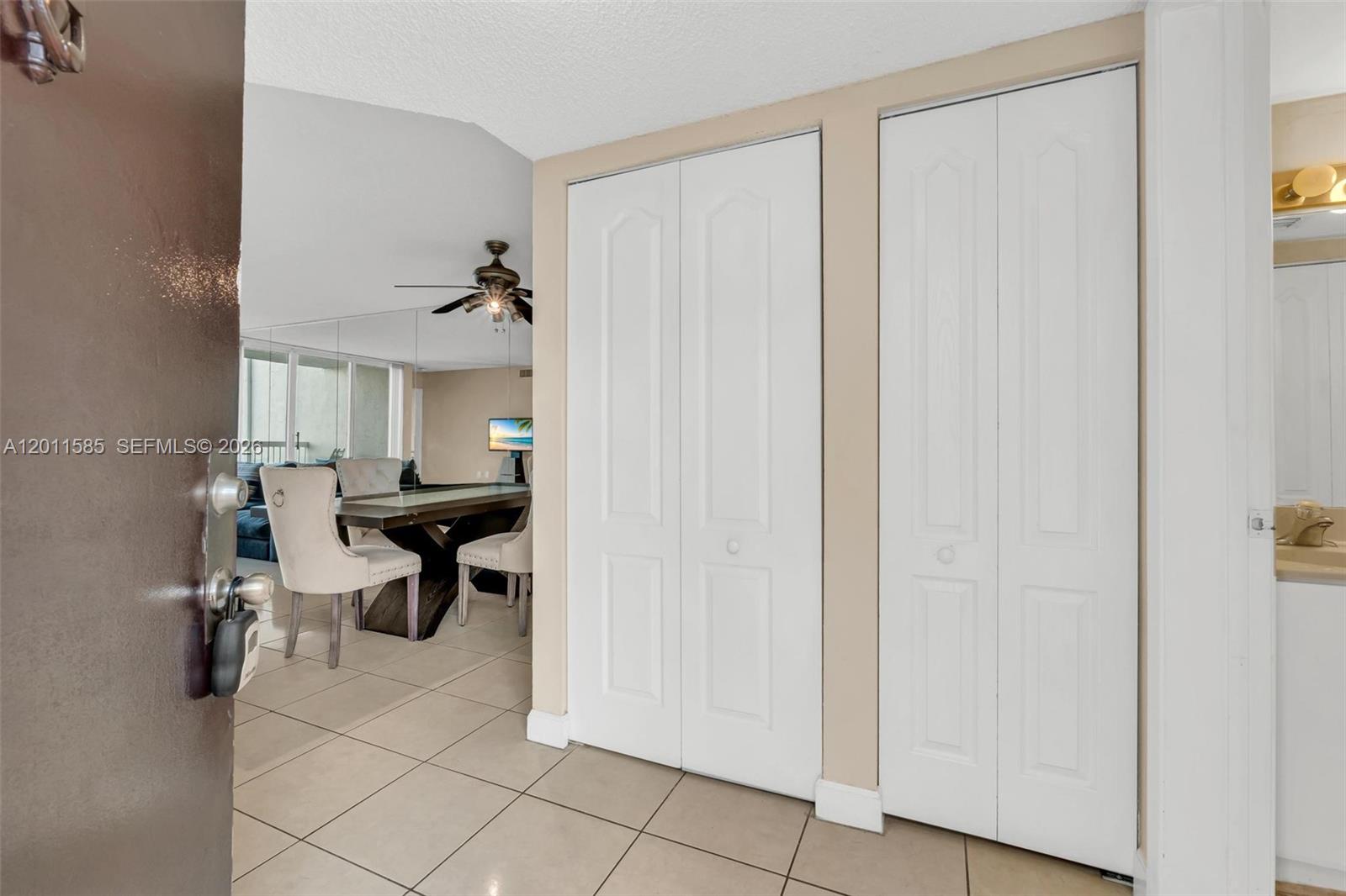 An entryway with tiled floors leads to a dining area with two white closet doors — 4647 NW 97th Pl # 151, Doral FL 33178, DORAL, FL