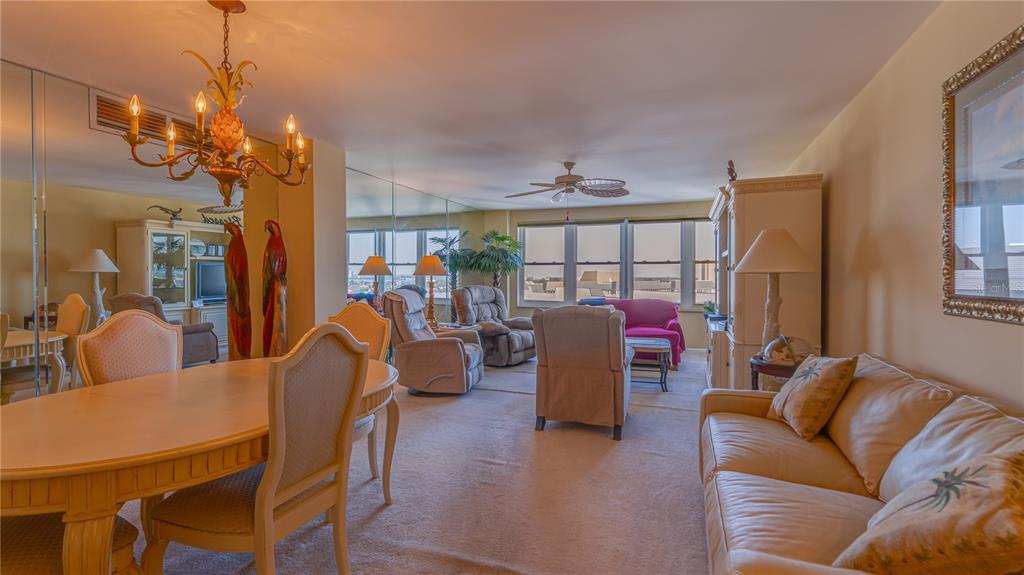 A dining area and living room with beige carpet, a chandelier, and large windows — 5200 BRITTANY DRIVE S UNIT 1201, ST PETERSBURG, FL