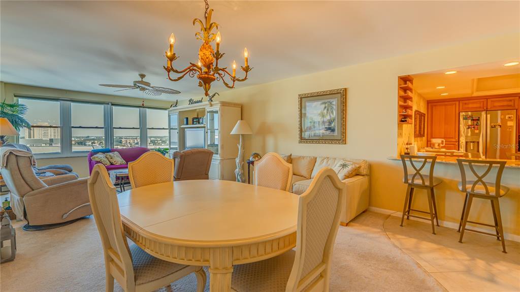 A dining area with a round table and chandelier opens to a living room and kitchen — 5200 BRITTANY DRIVE S UNIT 1201, ST PETERSBURG, FL