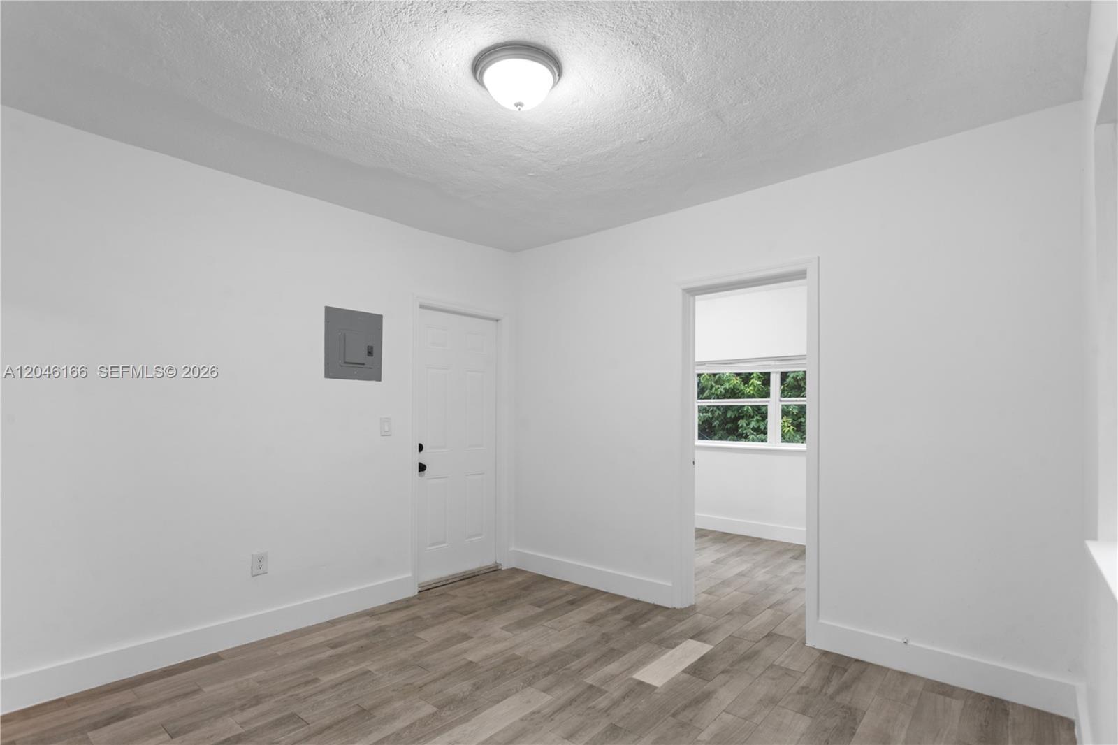 A room with white walls, light wood-look flooring, a ceiling light, and a doorway — 27 NE 60th Ter # 2, Miami FL 33137, MIAMI, FL