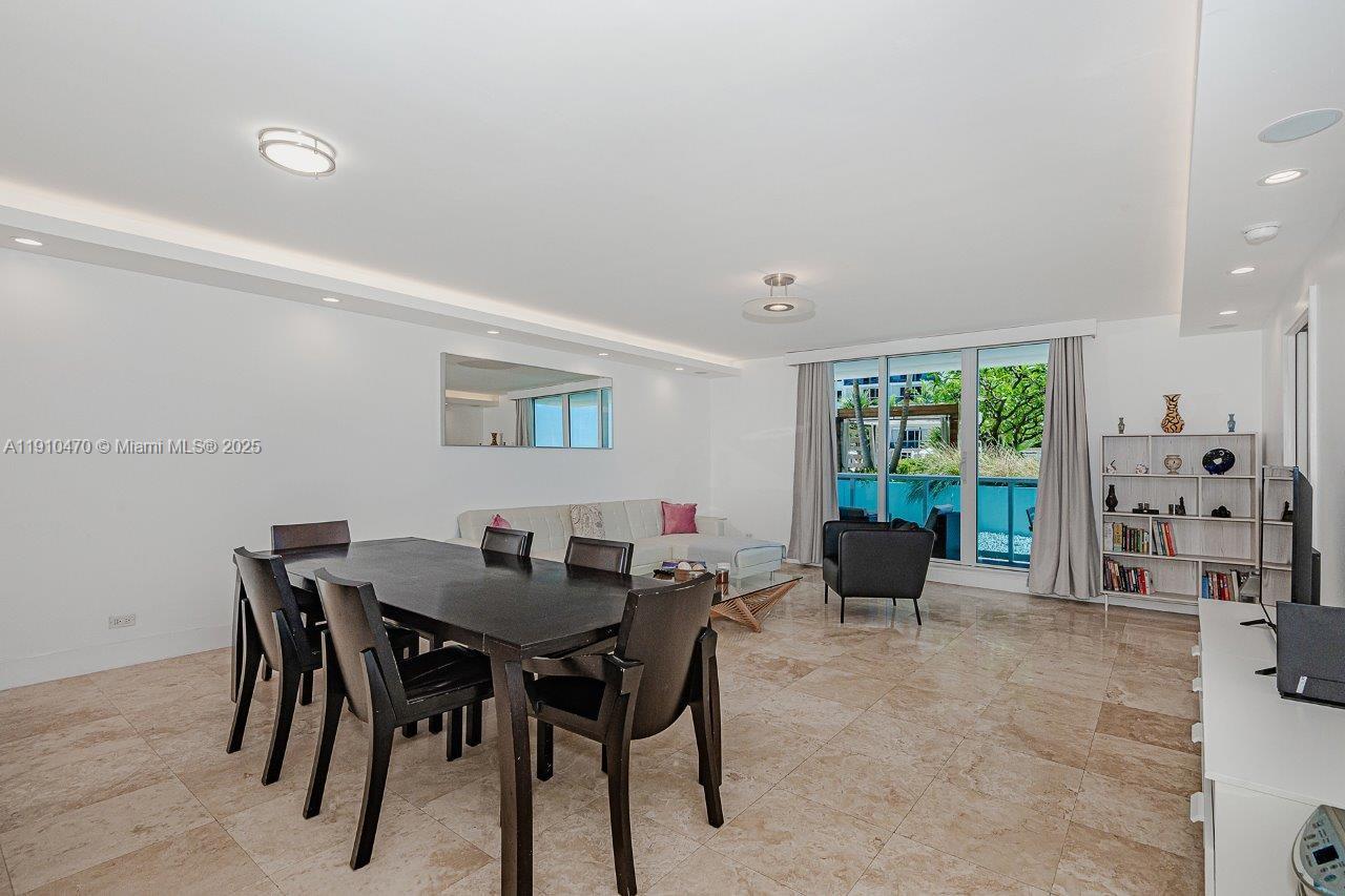 A dining and living area features tile flooring, a dark wood table, and floor-to-ceiling windows — 2301 Collins Ave # 310, Miami Beach FL 33139, MIAMI BEACH, FL