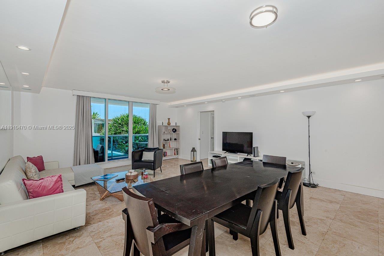A living and dining area features white walls, tile flooring, and a balcony view — 2301 Collins Ave # 310, Miami Beach FL 33139, MIAMI BEACH, FL