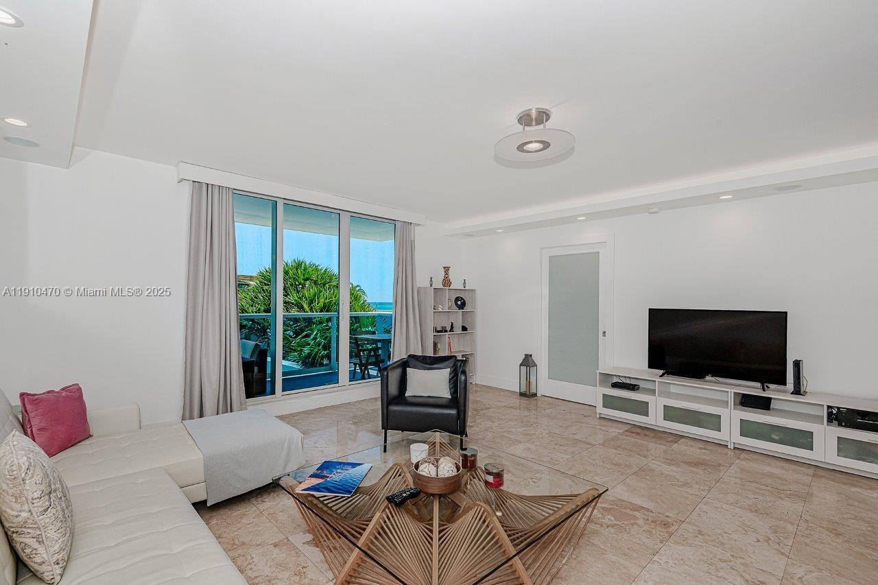 A living room features white walls, tile flooring, a sectional sofa, and floor-to-ceiling windows — 2301 Collins Ave # 310, Miami Beach FL 33139, MIAMI BEACH, FL