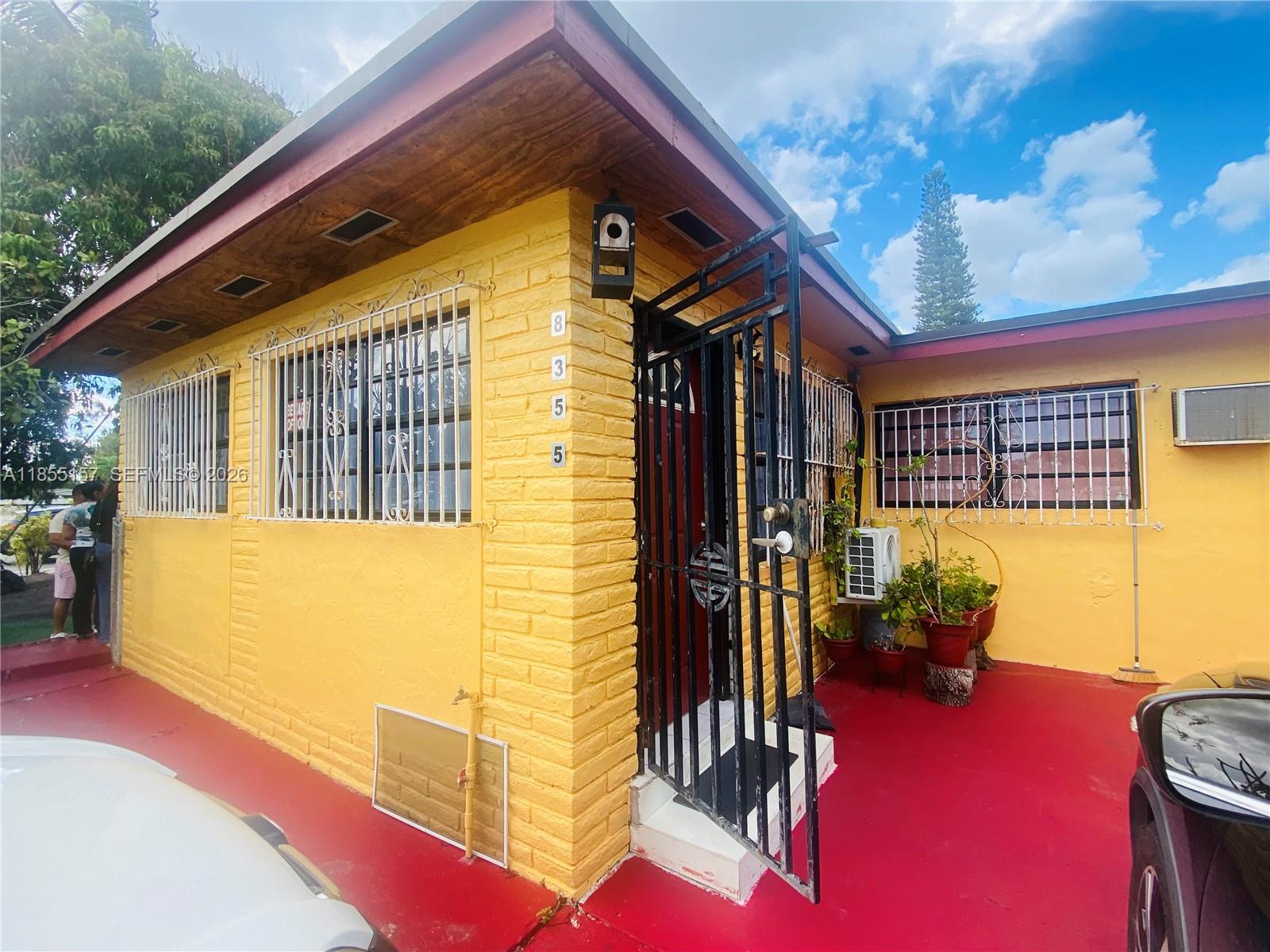 A yellow brick house features a red concrete patio and black security bars on windows — 8355 NW 32nd Ave, Miami FL 33147, MIAMI, FL