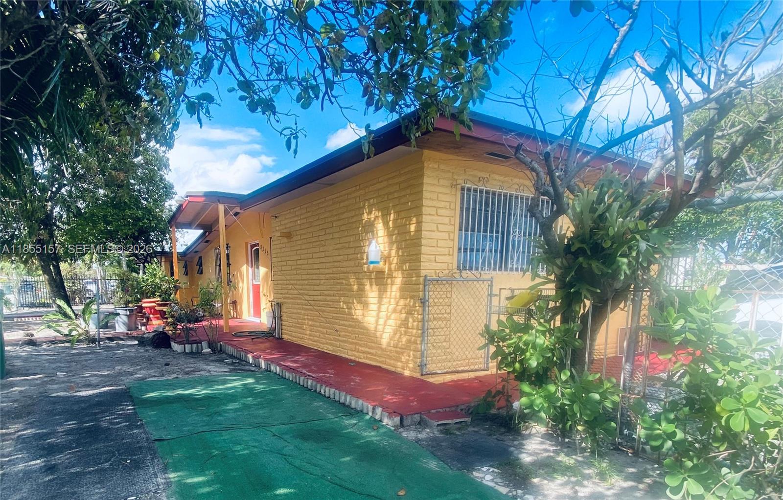 A yellow brick house with a red porch and a green mat in the yard — 8355 NW 32nd Ave, Miami FL 33147, MIAMI, FL