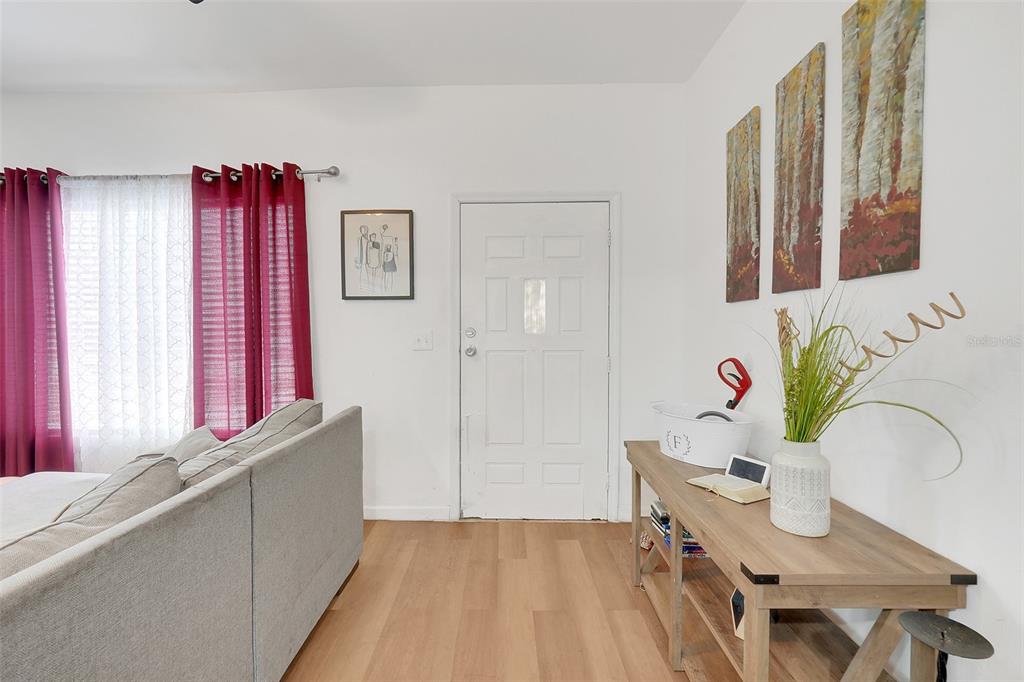 A living room features a white door, a gray sofa, and a wooden console table — 1313 4TH STREET NE, WINTER HAVEN, FL