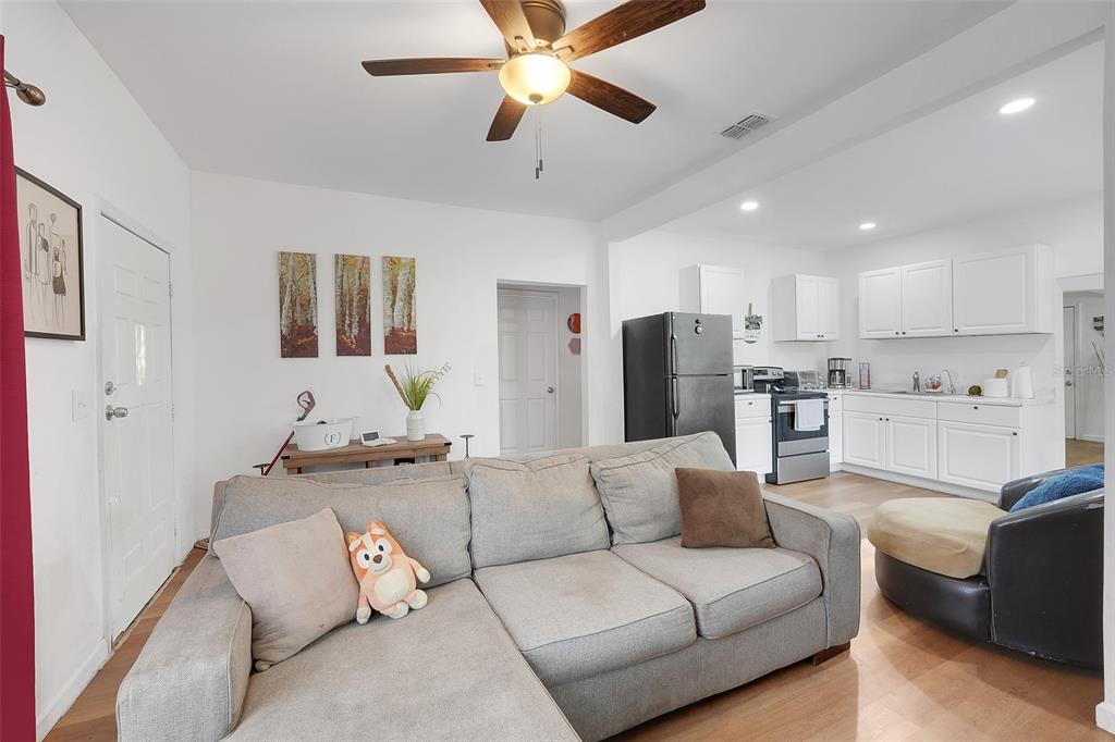 A living room with a gray sectional sofa opens to a kitchen with white cabinets — 1313 4TH STREET NE, WINTER HAVEN, FL