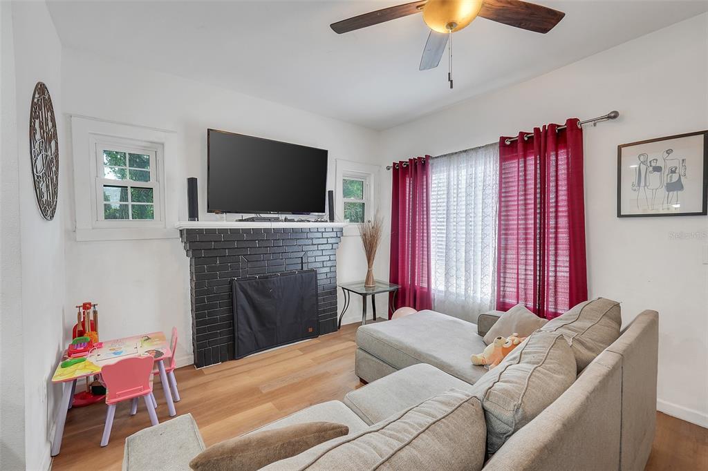 A living room features a black brick fireplace, a sectional sofa, and a children's table — 1313 4TH STREET NE, WINTER HAVEN, FL