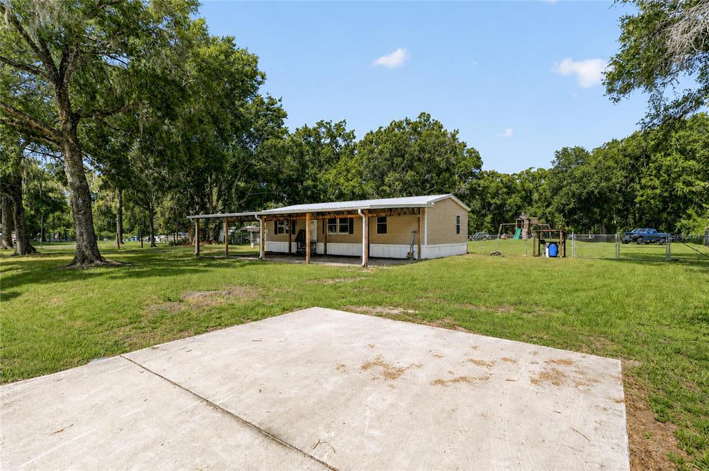 A single-story manufactured home with a covered porch sits on a large, grassy lot — 1708 ROBIN STREET, AUBURNDALE, FL