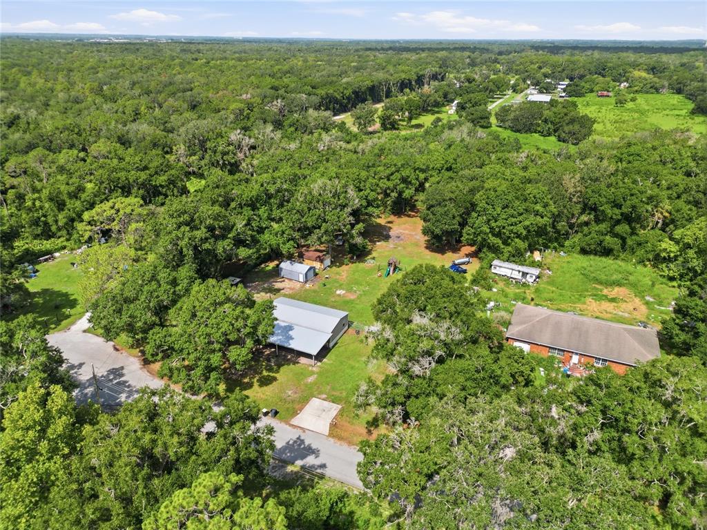 An aerial view shows a house, a large metal workshop, and outbuildings on a wooded lot — 1708 ROBIN STREET, AUBURNDALE, FL