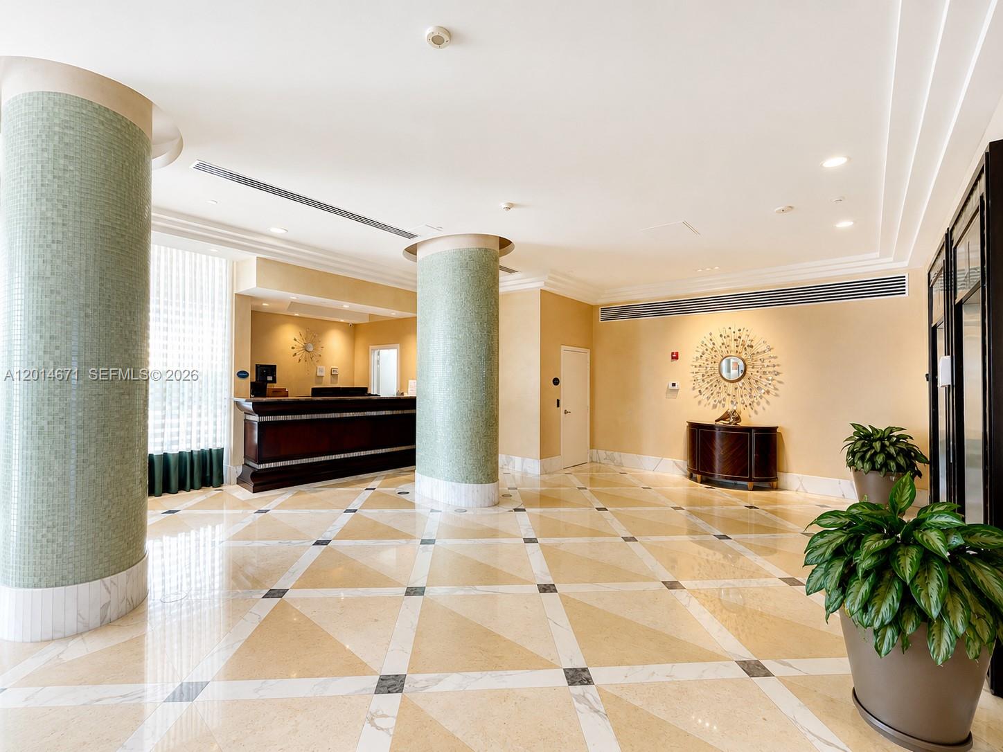 A lobby features tiled floors, two large mosaic-tiled columns, a reception desk, and decorative wall art — 6917 Collins Ave # 614, Miami Beach FL 33141, MIAMI BEACH, FL