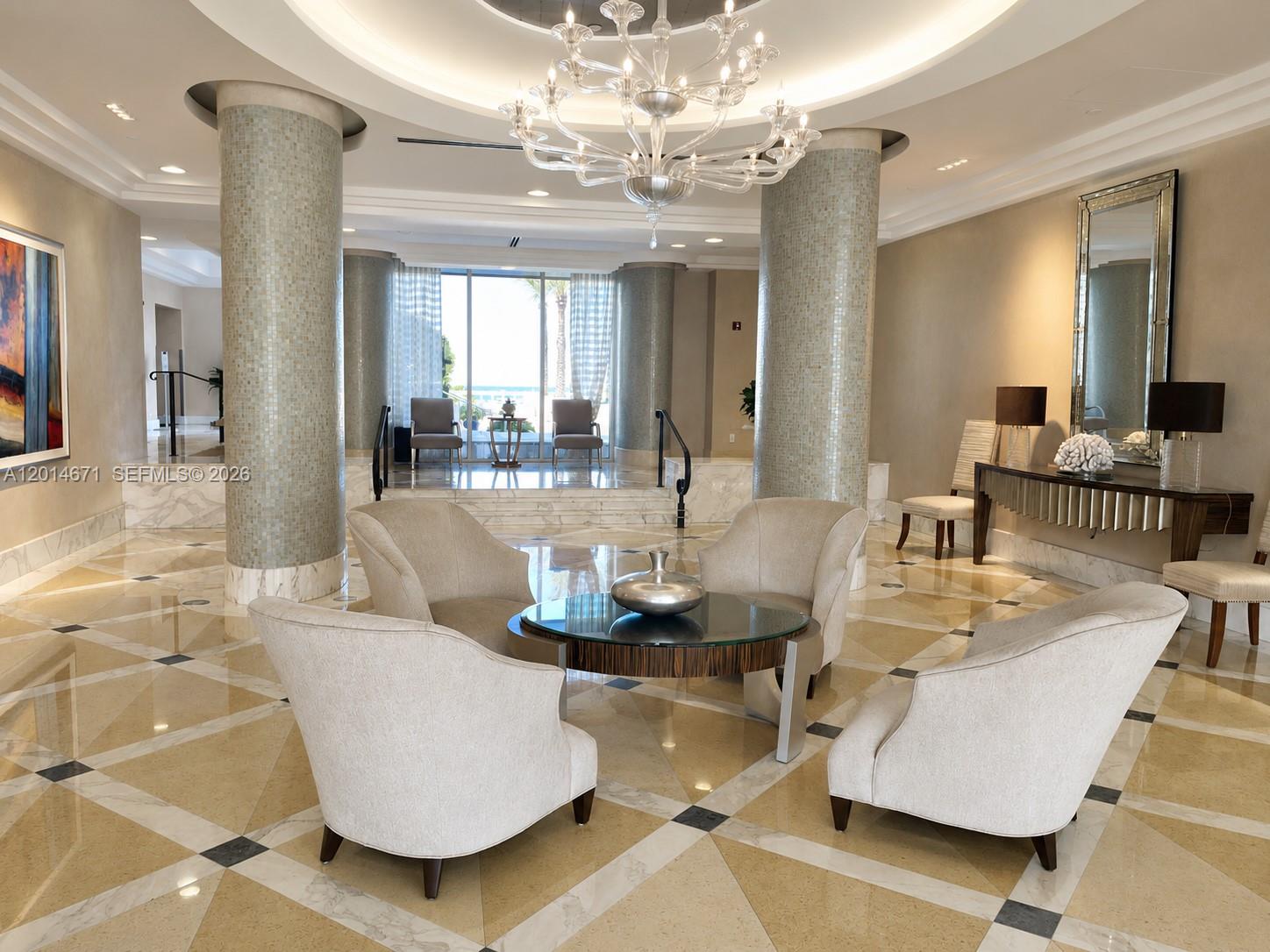 A lobby features a circular seating area with four armchairs, a glass table, and two tiled columns — 6917 Collins Ave # 614, Miami Beach FL 33141, MIAMI BEACH, FL