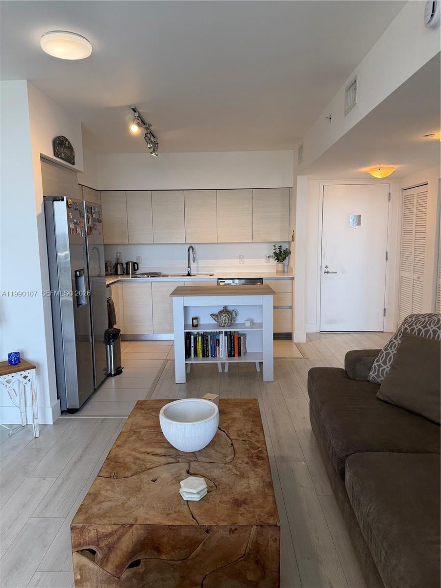 A kitchen with light wood cabinets and a central island sits adjacent to a living area — 4250 Biscayne Blvd # 1115, Miami FL 33137, MIAMI, FL