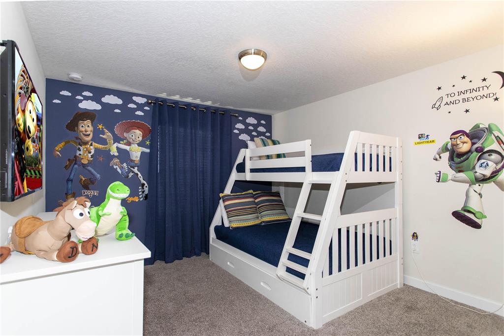 A child's bedroom features a white bunk bed, Toy Story wall decals, and blue curtains — 3078 JULIET DR, KISSIMMEE, FL