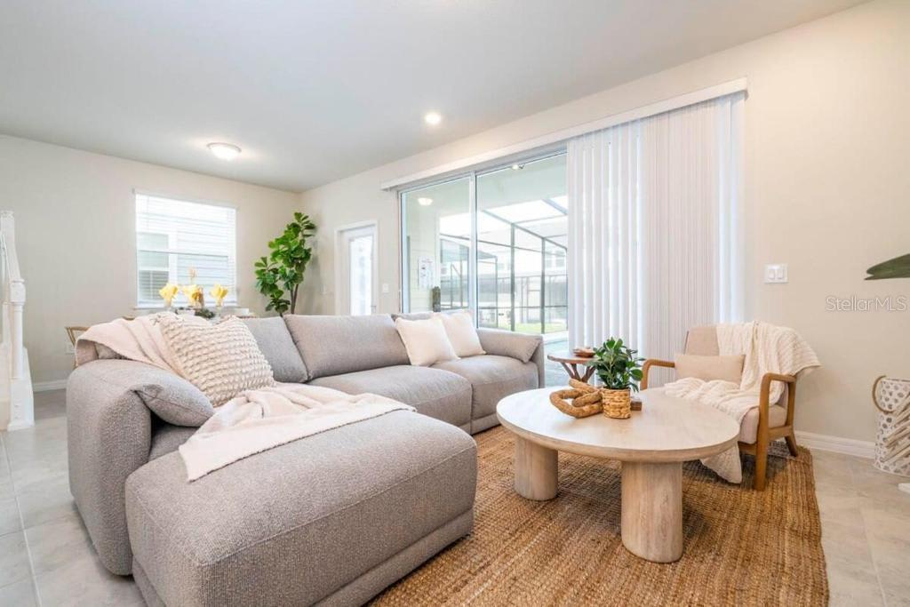 A living room features a gray sectional sofa, a round wooden coffee table, and sliding doors — 4106 LANA AVENUE, DAVENPORT, FL