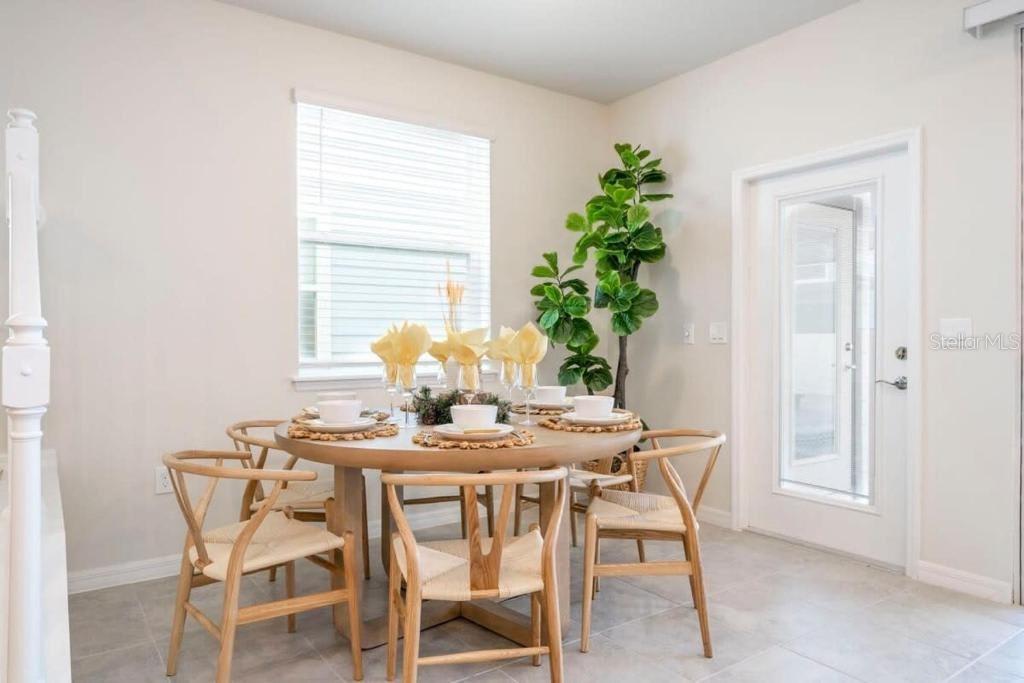 A dining area features a round wooden table with chairs, a large plant, and tile flooring — 4106 LANA AVENUE, DAVENPORT, FL