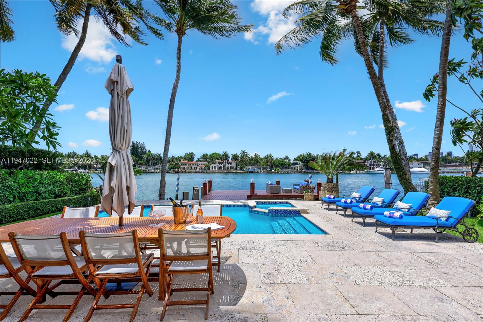 A patio features a dining set, pool, lounge chairs, and a dock overlooking the water — 56 S Hibiscus Dr, Miami Beach FL 33139, MIAMI BEACH, FL