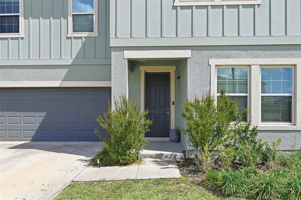 The exterior of a two-story house features a gray garage, a dark front door, and windows — 2162 DERWENT DRIVE, DAVENPORT, FL