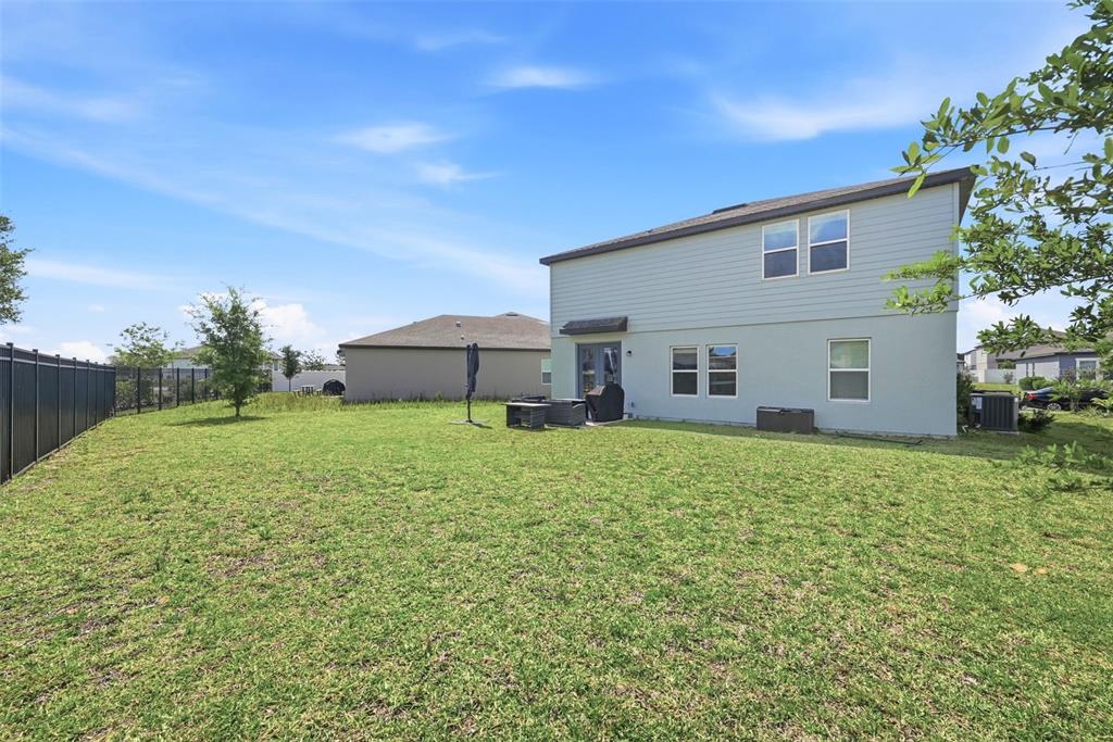 A two-story house exterior with a large grassy backyard and a black fence — 2162 DERWENT DRIVE, DAVENPORT, FL