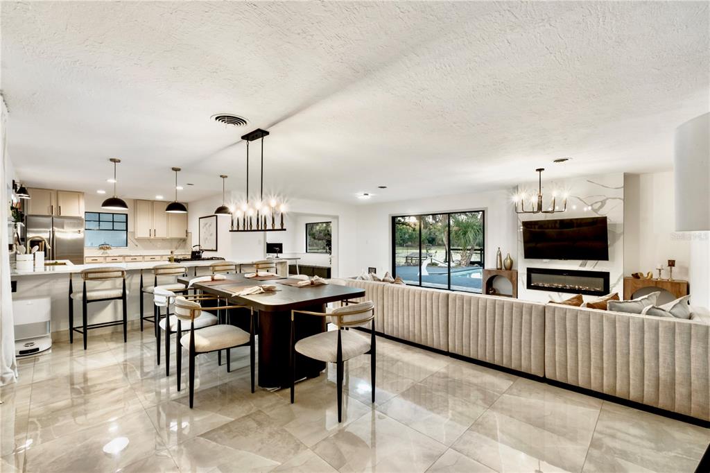 An open-concept living and dining area features tile flooring, a fireplace, and a kitchen island — 36245 E SPRING LAKE BOULEVARD, FRUITLAND PARK, FL