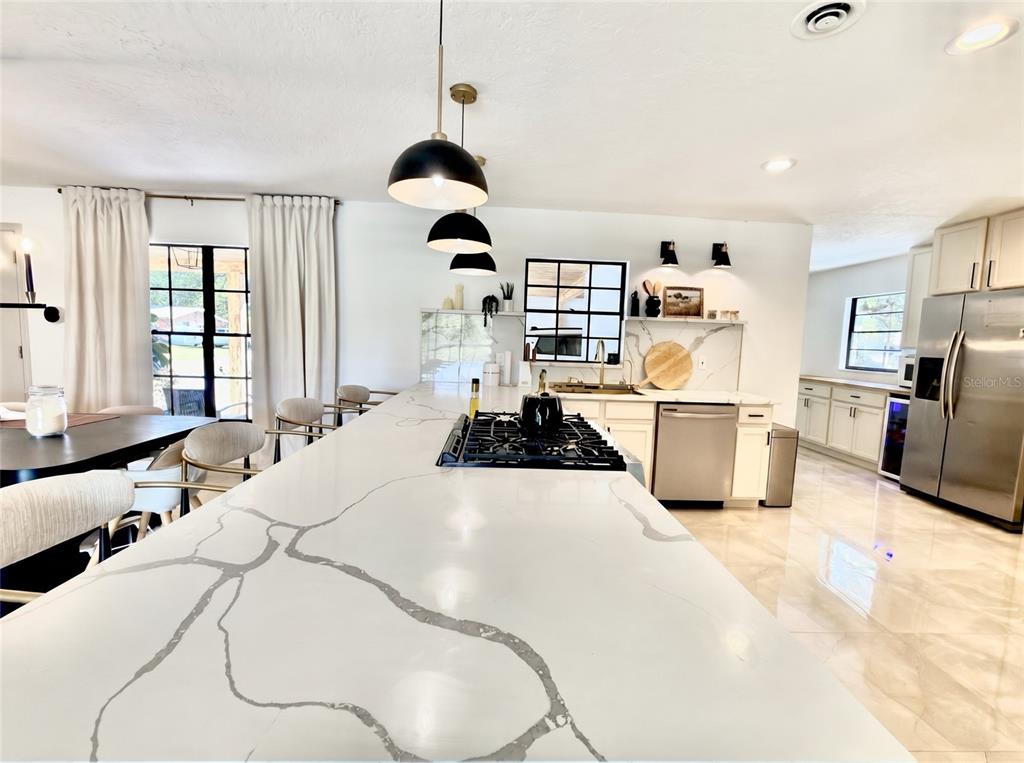 A kitchen features a large white quartz island with a gas cooktop and pendant lighting — 36245 E SPRING LAKE BOULEVARD, FRUITLAND PARK, FL
