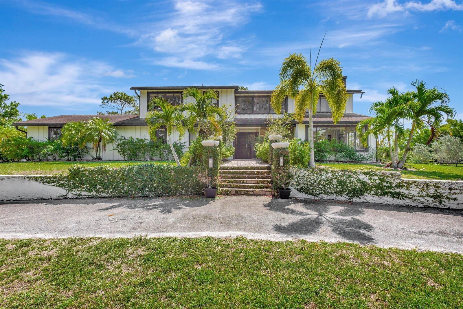 A two-story house with white siding, a brick staircase, and palm trees in the front — 5446 Reynolds Road, Lake Worth FL 33449, LAKE WORTH, FL